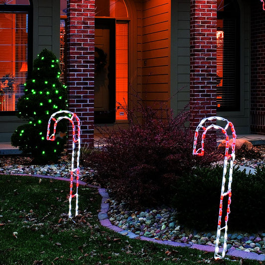 Candy Cane LED Displays in red and white LEDs stake-mounted along a front walkway beside a brick home at night