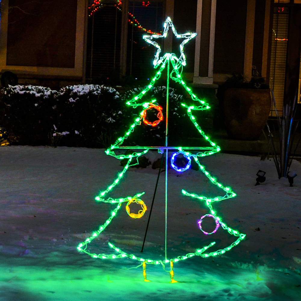 Christmas Tree with Ornaments LED display installed in snowy front yard at night, green LED outline with multicolor ornaments and glowing white star topper