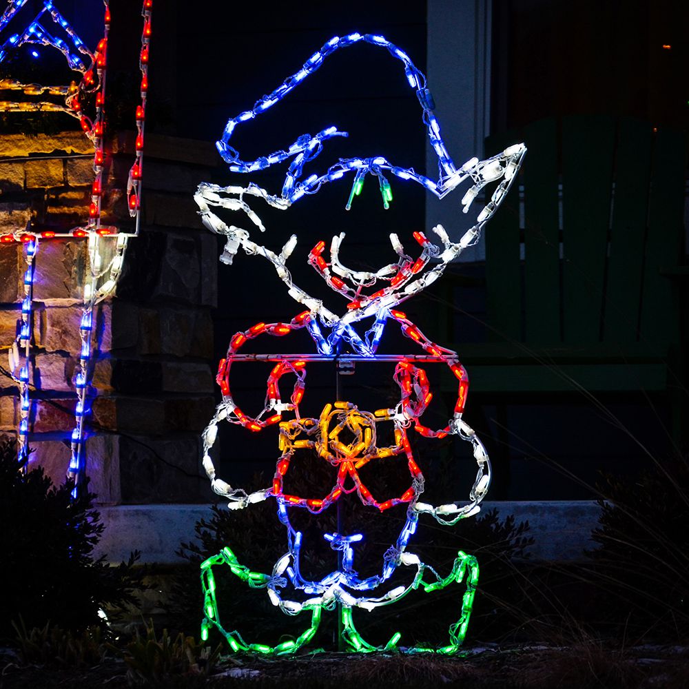North Pole elf Christmas light display lit up at night against a porch, glowing in red, blue and green mini LED lights.