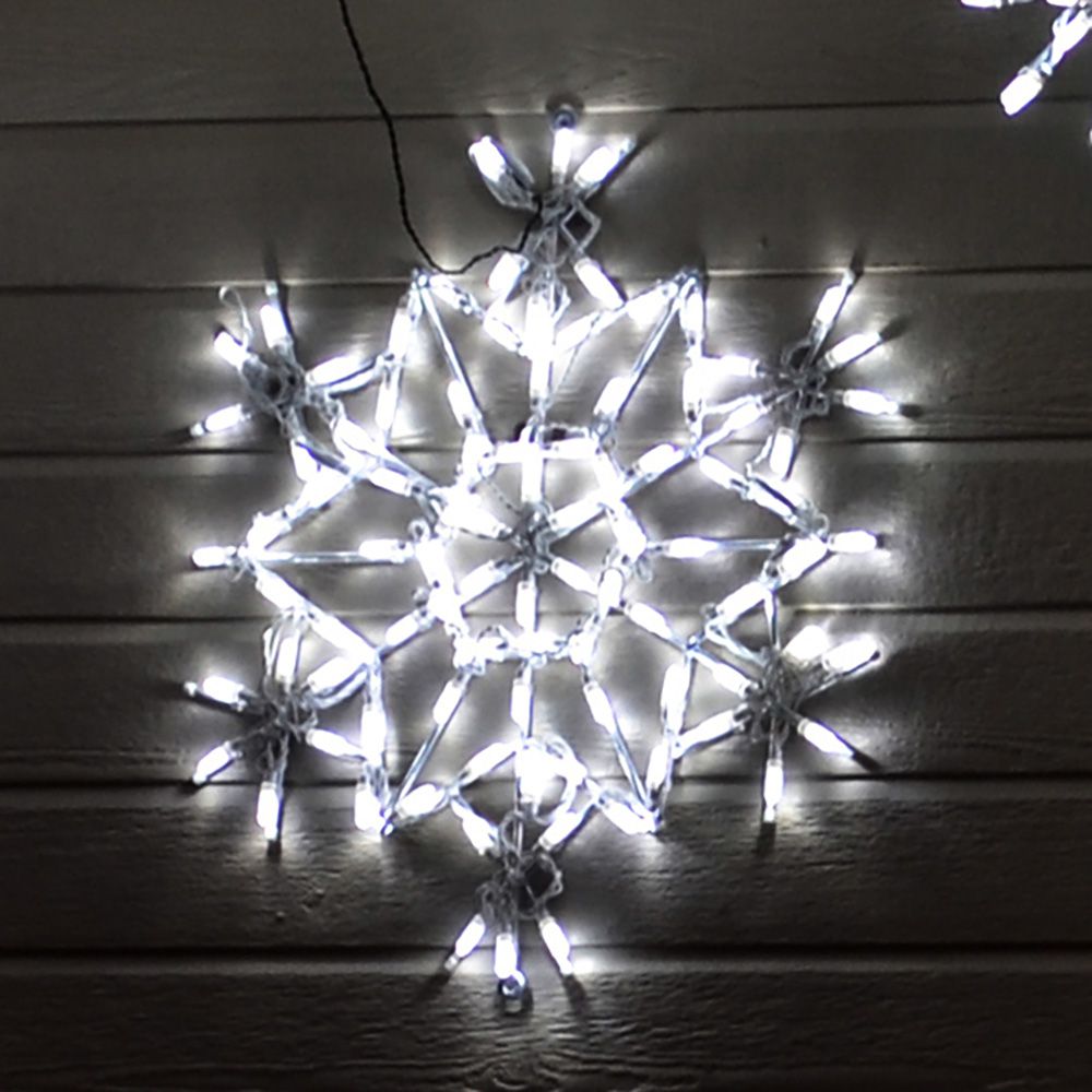 White Crystal Snowflake LED light display glowing against the side of a house at night