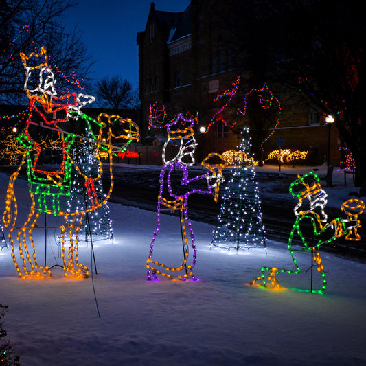 Wise Men LED nativity display installed outdoors in snow at night, three-piece set with wiseman on camel, standing wiseman holding gift, and kneeling wiseman with cup, multicolor rope lights