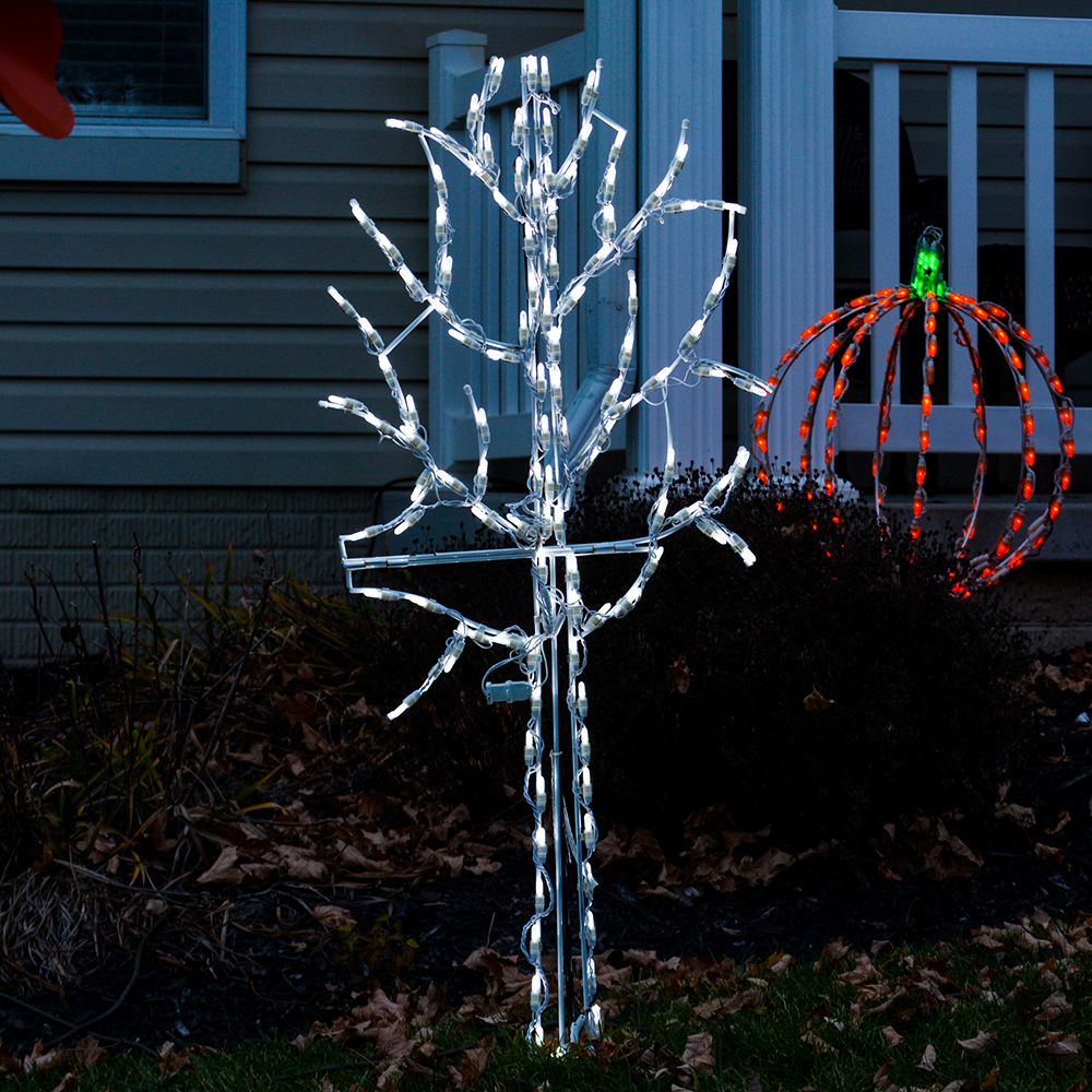 Winter Tree LED Display 4 ft. installed in front yard at dusk alongside an orange and green LED pumpkin display, white LED bare-branch silhouette against a residential home